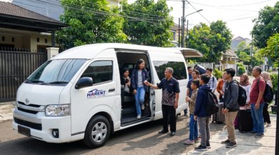 Rombongan liburan bersiap masuk ke dalam Toyota Hiace Commuter 14 kursi dari layanan sewa mobil.